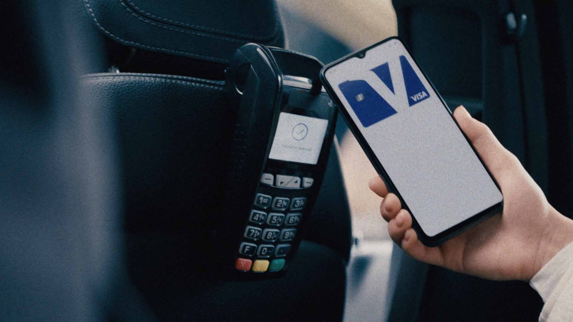Phone with image of Visa card and logo held up to a card reader.